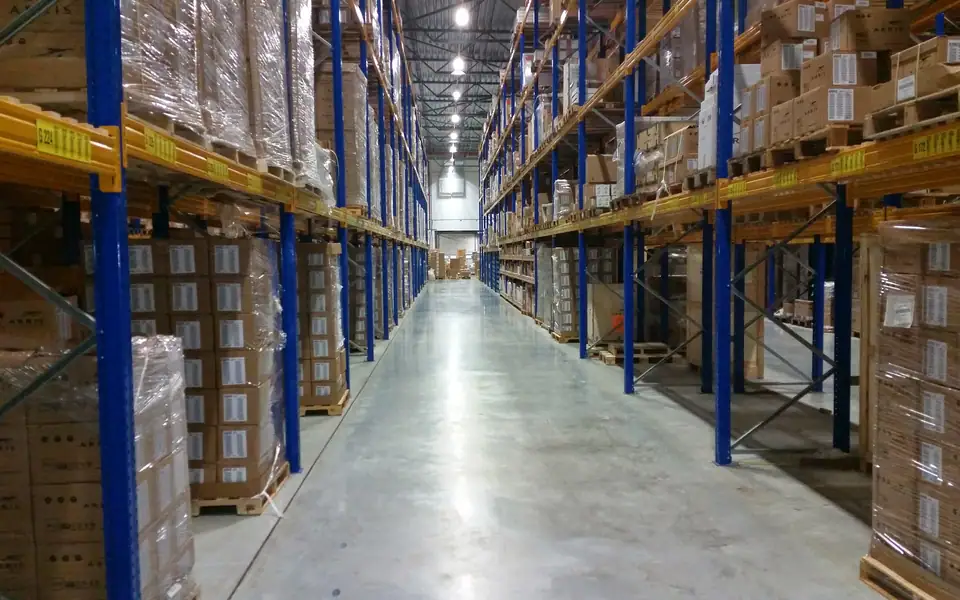 Cartons stored on blue and gold warehouse racking beside a clear aisle.